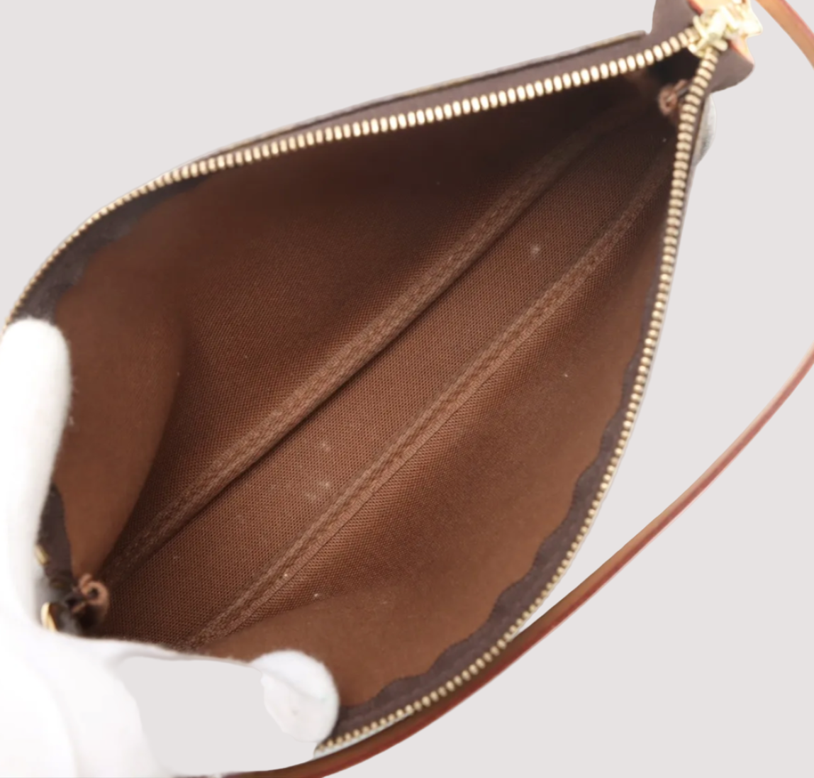 Close-up of a brown leather handbag with gold zipper on a white background